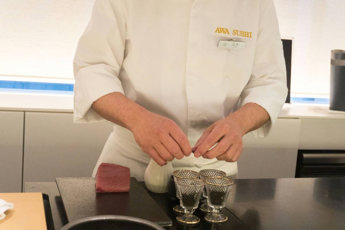 Kuhar v beli uniformi za pultom reže meso.