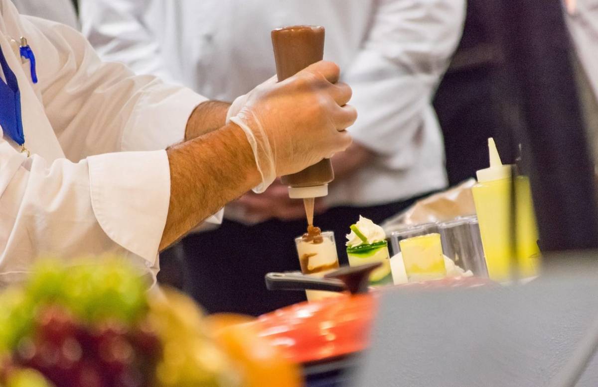 Chef med pripravljanjem jedi v profesionalni kuhinji.